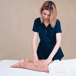 Woman giving Swedish body massage therapy to the calf muscles
