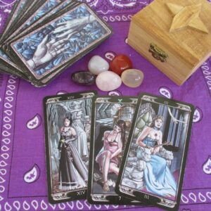 Tarot cards and crystals on a purple sheet with a wooden box